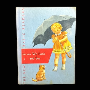 Puede incluir: Portada de libro infantil vintage, "The New We Look and See". Presenta una ilustración de un niño con un vestido amarillo sosteniendo un paraguas, con un perro. El fondo es azul claro. Parte de la serie "Basic Readers".