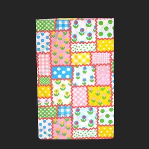 May include: A rectangular fabric piece featuring a patchwork design of various patterns including green and white gingham, blue and white checks, polka dots, and floral motifs in yellow, pink, blue, and green, all separated by red zigzag borders.