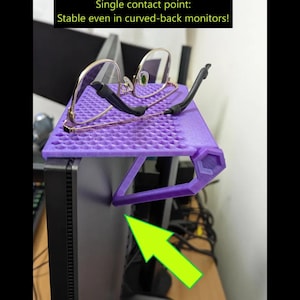 May include: A purple monitor shelf with a honeycomb pattern, holding a pair of gold-rimmed glasses. The shelf is supported by a purple bracket and is attached to a computer monitor. Text on the image reads: "Single contact point: Stable even in curved-back monitors!"