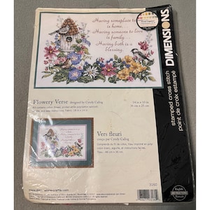 May include: A Dimensions Flowery Verse stamped cross stitch kit in plastic packaging. The design features a birdhouse, birds, and colorful flowers with the text: Having someplace to go is home... Having someone to love is family... Having both is a blessing. The kit measures 14 inches by 10 inches.