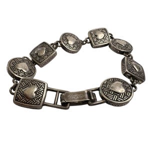 K&ouml;nnte beinhalten: Silberfarbenes Armband mit herzf&ouml;rmigen Akzenten in quadratischen, runden und rautenf&ouml;rmigen Gliedern. Das Armband hat ein strukturiertes Muster und einen Verschluss mit dem Markennamen "Brighton".