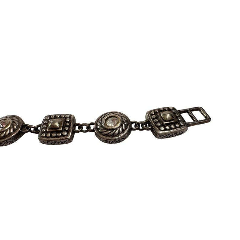 K&ouml;nnte beinhalten: Silberfarbener Metallg&uuml;rtel mit dekorativen quadratischen und runden Verzierungen. Der G&uuml;rtel hat ein Kettendesign und einen rechteckigen Verschluss. Die Verzierungen haben eine strukturierte, antike Oberfl&auml;che und einen kleinen, klaren Stein in der Mitte.