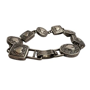 K&ouml;nnte beinhalten: Silberfarbenes Armband mit herzf&ouml;rmigen und quadratischen Anh&auml;ngern mit aufwendigen Webmustern. Das Armband hat einen Verschluss mit dem eingravierten Markennamen "Brighton". Ein stilvolles Accessoire.