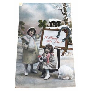 Cartão postal colecionável vintage: duas meninas paradas na neve ao lado da placa "Feliz Ano Novo"