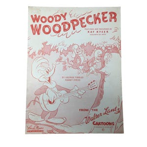 Puede incluir: Partitura vintage de "Woody Woodpecker" con el personaje de dibujos animados tocando la guitarra. La portada es principalmente rosa y blanca, con el título en letras rojas grandes. La partitura es de los dibujos animados de Walter Lantz.