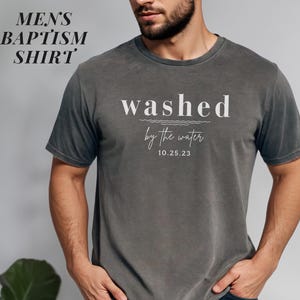 May include: A gray t-shirt with the text "washed by the water 10.25.23" printed in white.