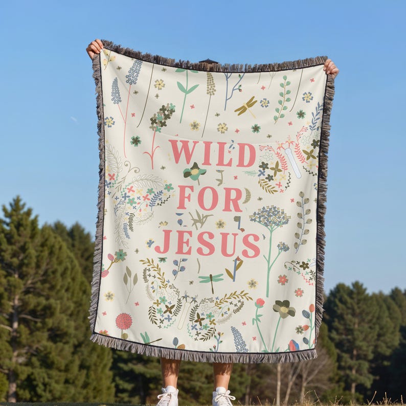 May include: A white woven throw blanket with a floral pattern and the text "WILD FOR JESUS" in pink letters. The blanket has a fringe border.