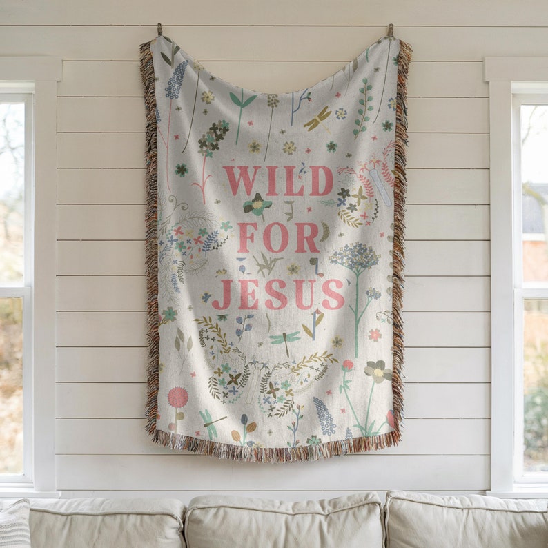 May include: A woven throw blanket with a white background and a floral pattern. The text "WILD FOR JESUS" is printed in pink on the blanket.