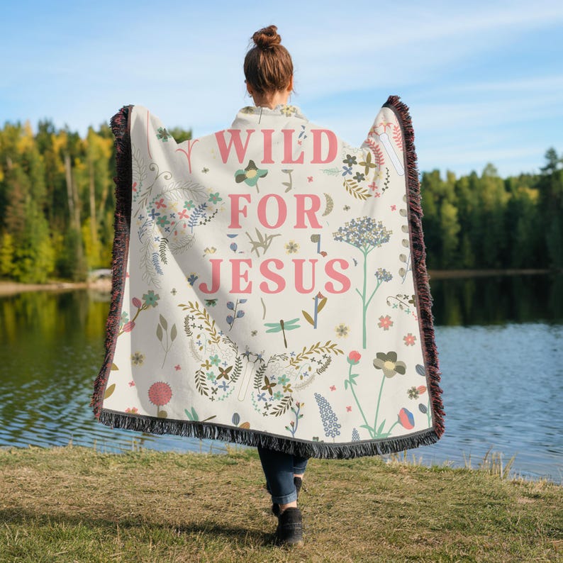 May include: A white woven throw blanket with a floral pattern and the text "WILD FOR JESUS" in pink. The blanket has fringe on the edges.