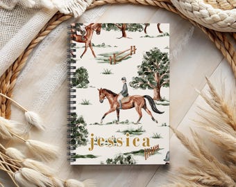 May include: A spiral-bound notebook with a cream-colored cover featuring a watercolor equestrian scene. The design includes riders on horseback, trees, and fences. The name "Jessica" is written in gold script across the bottom.
