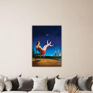 May include: A canvas print depicts a woman seated in a chair, gazing at a night sky with a crescent moon and a city skyline. The woman wears a red skirt and a blue top. The artwork has a surreal, dreamlike quality.