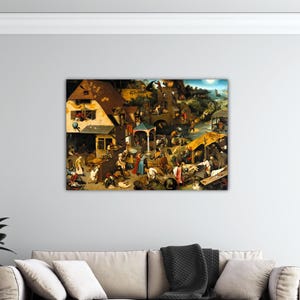 May include: A framed canvas print of a detailed, historical painting depicting a bustling village scene. The artwork features numerous figures engaged in various activities, with buildings and natural elements in warm, earthy tones.