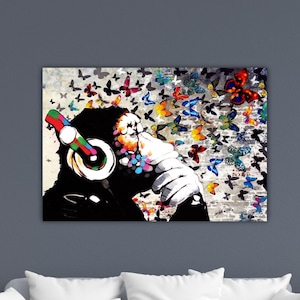 May include: A vibrant canvas print featuring a person wearing colorful headphones, with a face partially obscured by colorful paint splatters. The background is filled with a multitude of butterflies in various colors.