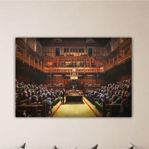 Op de afbeelding: Een schilderij dat een kamer vol chimpansees laat zien, gekleed in pakken, zittend in een parlementaire setting. De chimpansees zitten in rijen, met het gezicht naar een podium, met een groot raam achter hen. De kamer is versierd met sierlijke houten lambrisering en kroonluchters.