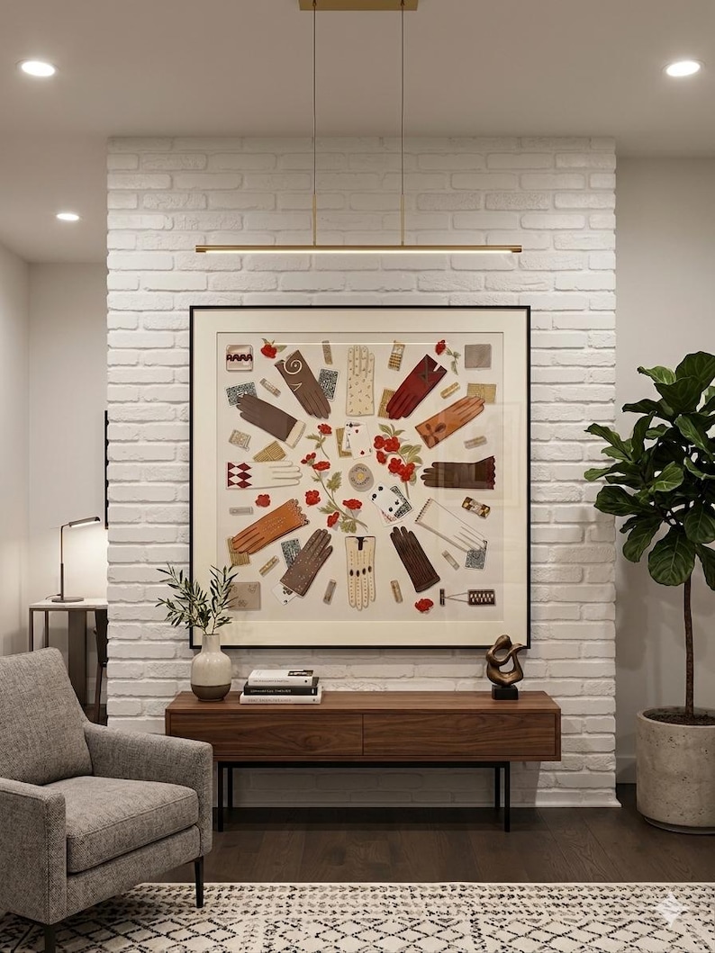 Puede incluir: Una gran obra de arte cuadrada enmarcada que presenta un collage de guantes de cuero de varios colores dispuestos en un patr&oacute;n circular con detalles florales rojos, sobre una pared de ladrillo blanco y una consola de madera larga.