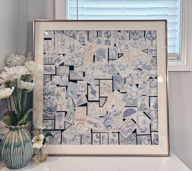 Puede incluir: Una pieza de arte mural cuadrada enmarcada que presenta un collage de numerosos sellos postales azules y blancos. Los sellos muestran varias ilustraciones, incluyendo globos terr&aacute;queos, sillas y motivos arquitect&oacute;nicos. La obra est&aacute; en un marco met&aacute;lico.