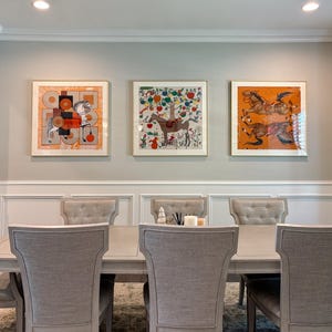 Puede incluir: Un juego de comedor con una mesa rectangular de madera clara rodeada por seis sillas tapizadas con respaldos capiton&eacute;. Tres l&aacute;minas de arte cuadradas y enmarcadas que representan caballos y patrones coloridos est&aacute;n montadas en la pared.