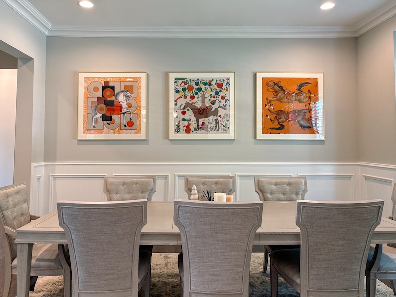 Puede incluir: Un juego de comedor con una mesa rectangular de madera clara rodeada por seis sillas tapizadas con respaldos capiton&eacute;. Tres l&aacute;minas de arte cuadradas y enmarcadas que representan caballos y patrones coloridos est&aacute;n montadas en la pared.