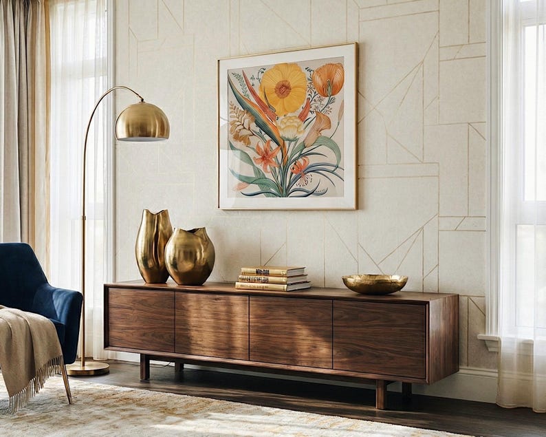 Puede incluir: Un mueble multimedia de madera largo y rectangular con cuatro puertas de armario, coronado con dos jarrones met&aacute;licos dorados, una pila de tres libros y un cuenco dorado poco profundo, situado bajo una l&aacute;mina bot&aacute;nica con flores amarillas y naranjas.