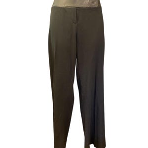 Puede incluir: Pantalones negros de pierna ancha con una cintura alta y ancha de color marrón oscuro con aspecto de cuero. Los pantalones tienen un diseño clásico y a medida, adecuado para diversas ocasiones. La tela parece ser de color liso y suave.