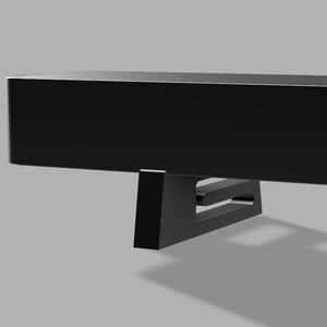 Pu&ograve; includere: Una mensola nera e rettangolare dal design minimalista. La mensola &egrave; sostenuta da un supporto angolare nero. Il supporto ha un design ritagliato. La mensola e il supporto sono su sfondo grigio.