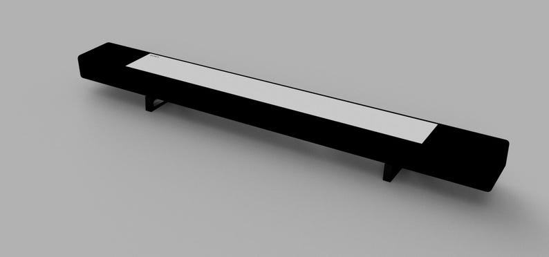 May include: A long, black rectangular shelf with a white top. The shelf is supported by two metal legs on each end.