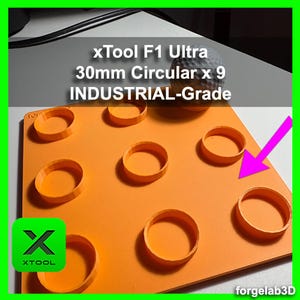 Op de afbeelding: Een set van negen 30 mm ronde mallen op een oranje oppervlak. De mallen zijn gemaakt van een duurzaam, industrieel materiaal. De tekst "xTool F1 Ultra 30mm Circular x 9 INDUSTRIAL-Grade" is zichtbaar bovenaan de afbeelding.