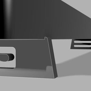 Pu&ograve; includere: Primo piano di un oggetto grigio scuro angolato con un ritaglio rettangolare e un supporto a forma di U. L'oggetto ha una finitura lucida ed &egrave; ambientato su uno sfondo grigio chiaro. Il design suggerisce un'estetica moderna.