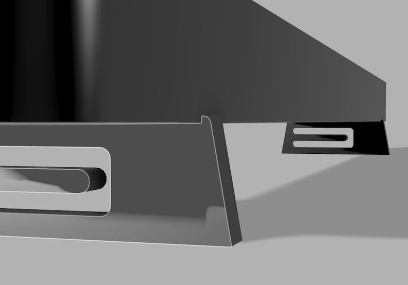 Pu&ograve; includere: Primo piano di un oggetto grigio scuro angolato con un ritaglio rettangolare e un supporto a forma di U. L'oggetto ha una finitura lucida ed &egrave; ambientato su uno sfondo grigio chiaro. Il design suggerisce un'estetica moderna.