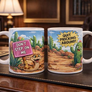 Peut inclure: Deux mugs en céramique blanche avec des illustrations humoristiques sur le thème du désert. L'un des mugs représente un serpent avec un panneau indiquant "Don't Step on Me". L'autre mug a un cactus avec le texte "Quit Pricking Around!"