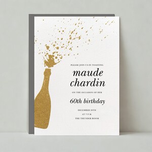 May include: A gold glitter champagne bottle with a spray of gold glitter, a white invitation with black text that reads "Please join us in toasting Maude Chardin on the occasion of her 60th birthday December 20th at 7 PM The Thunder Room"