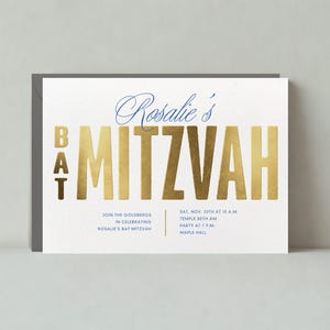 May include: A white invitation card with gold foil lettering announcing a Bat Mitzvah for Rosalie. The text reads "Rosalie's Bat Mitzvah" and includes the date, time, and location of the event.