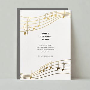 May include: A white invitation with gold musical notes printed on it. The invitation reads "Tom's Turning Seven" and includes the date and time of the event: "Saturday, November 30th at 2:30 PM". The invitation also includes the location: "The Sawyer Residence".