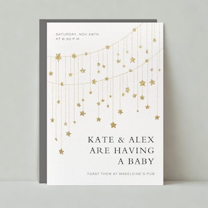 Puede incluir: Una tarjeta blanca con estrellas doradas de brillantina colgando de cuerdas. El texto en la tarjeta dice "SÁBADO, NOV 29TH A LAS 6:30 PM. KATE & ALEX ESTÁN TENIENDO UN BEBÉ BRINDA POR ELLOS EN MADELEINE'S PUB"