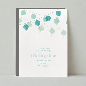 May include: A white card with a blue watercolor illustration of string lights. The text on the card reads "Put on your apron and grab the tongs it's bbq time Saturday, July 10th at noon Our backyard"