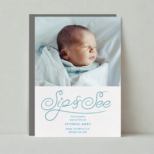 May include: A white card with blue cursive text that reads "Sip & See" and a photo of a baby sleeping in a white blanket. The text below the photo reads "You're invited to meet our little one COTTONTAIL RABBIT Sunday, July 28th at 2 p.m. McGovern Farm Cafe"