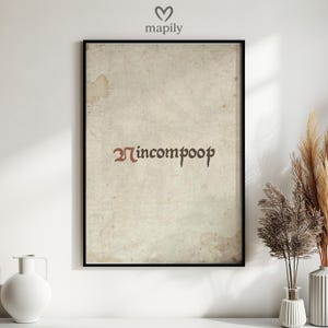 Może przedstawiać: Oprawiony wydruk artystyczny ze słowem "incompoop" w gotyckiej czcionce. Wydruk ma wygląd vintage, postarzanego papieru z brązowymi plamami. Rama jest czarna, a grafika jest wyświetlana na białej ścianie.