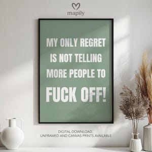 Op de afbeelding: Een ingelijste print met de tekst "MY ONLY REGRET IS NOT TELLING MORE PEOPLE TO FUCK OFF!" in wit op een saliegroene achtergrond. De print wordt gepresenteerd met decoratieve vazen en gedroogde planten.