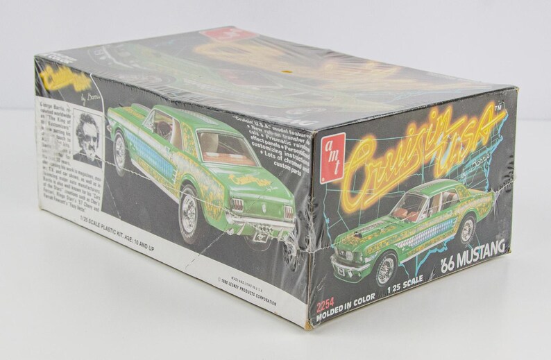 Puede incluir: Caja de kit de modelo de coche vintage con un Mustang '66 verde y azul. La caja tiene las palabras "Cruisin' USA" en amarillo y el texto "Molded in Color". La caja es a escala 1/25 y es para mayores de 10 a&ntilde;os.