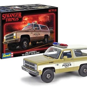 Pode incluir: Um kit de modelo do Chevrolet K5 Blazer 1985 de Jim Hopper da s&eacute;rie Netflix Stranger Things. O modelo &eacute; pintado em um esquema de cores bege e branco com as palavras "Hawkins Police Dept." no lado. O modelo tamb&eacute;m possui uma barra de luzes vermelha e azul no teto.