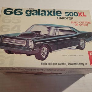 May include: A vintage model kit box for a '66 Ford Galaxie 500XL Hardtop. The box features a dark green car illustration, with text that reads "Build Custom or Stock." The box is beige and red.