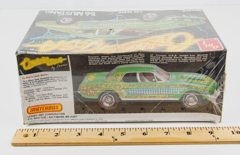 Puede incluir: Un kit de modelo de coche antiguo de un Mustang 1966 verde y dorado. La caja presenta el texto "Cruisin' by Barris" y "Matchbox". El modelo de coche est&aacute; decorado con dise&ntilde;os intrincados y es a escala 1/25.