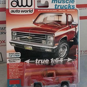 May include: A red die-cast metal Chevrolet Silverado K10 Stepside pickup truck model. The model is a limited edition, 1:64 scale, with rubber tires and an opening hood. The packaging includes the "Auto World" and "Muscle Trucks" logos.