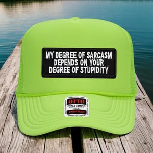 May include: A neon green trucker hat with a black patch that reads "MY DEGREE OF SARCASM DEPENDS ON YOUR DEGREE OF STUPIDITY" in white text. The hat has a mesh back and a curved brim. A small white sticker is on the brim.