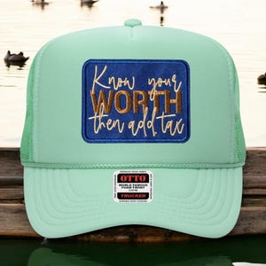 May include: A mint green trucker hat featuring a rectangular blue patch with gold embroidered text that reads Know your WORTH then add tax. The hat includes a foam front panel, mesh side panels, and a small white sticker on the brim.