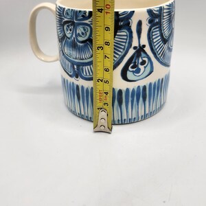May include: A ceramic mug with a white interior and a blue and white floral design. The mug is approximately 4 inches tall. The handle is white. The mug is on a white background.