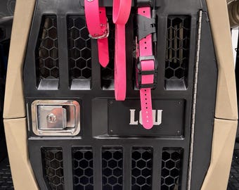 May include: A tan and black pet crate with a honeycomb ventilation pattern and a metal locking mechanism. Three bright pink collars are hanging from the top of the crate door. The word LOU is printed in white letters on the black center panel.