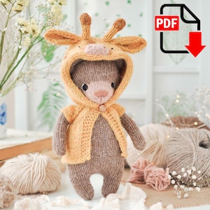 Pode incluir: Um urso de peluche marrom de malha vestindo um traje de girafa amarelo de malha com fecho de botão. O urso está em pé sobre uma superfície branca com fio e flores no fundo.