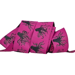 May include: Pink ribbon with a black octopus print. The ribbon is folded and shows the pattern on both sides.