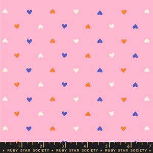 Könnte beinhalten: Rosa Stoff mit einem sich wiederholenden Muster aus kleinen Herzen in Weiß, Orange und Blau. Der Text "RUBY STAR SOCIETY" ist am unteren Rand aufgedruckt.